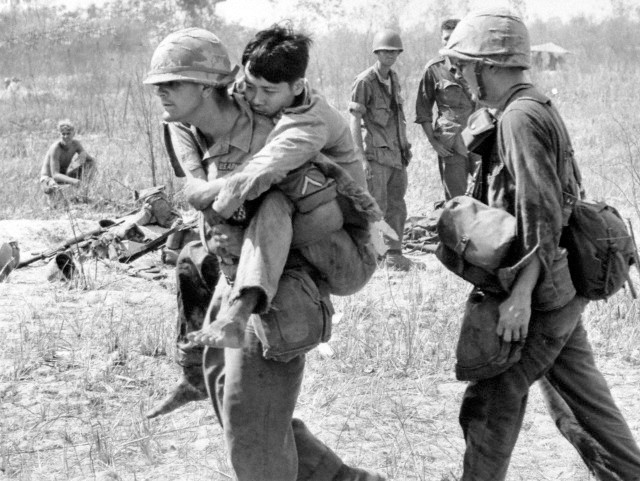 05 Mar 1966, Vietnam --- Pfc. John Stananback of East Paterson, N.J., carries a Viet Cong soldier on his back to a first aid station near Bau Bang, 30 miles north of Saigon