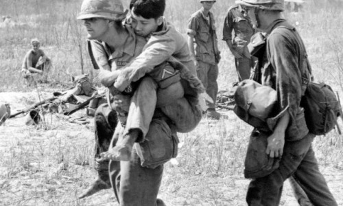 05 Mar 1966, Vietnam --- Pfc. John Stananback of East Paterson, N.J., carries a Viet Cong soldier on his back to a first aid station near Bau Bang, 30 miles north of Saigon