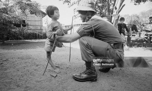 Aussie Help for Crippled Girl. Saigon, South Vietnam: Her legs twisted and deformed, a tiny Vietnamese girl struggles into the arms of an Australian soldier during the recent Operation Haymen. Under the care of Australian medical teams, [. . .] little girl will soon be walking without the aid of bamboo crutches. November 12, 1966.