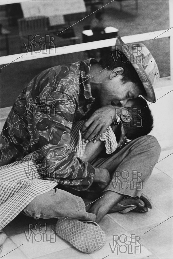 Vietnam War. Wounded child at the hospital with his father, he died a few days later. Saigon, 1975