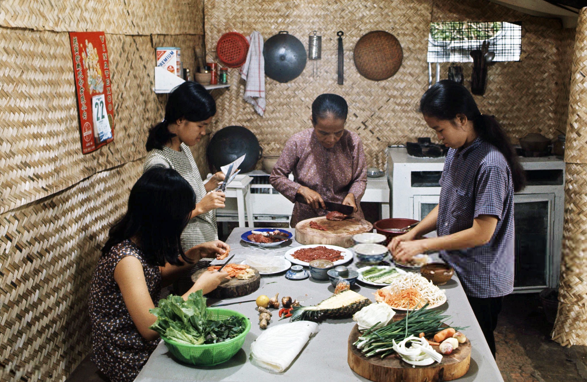 Tấm hình này thể hiện hình ảnh người mẹ cùng 3 cô con gái đang chuẩn bị cho bữa ăn. Bà mẹ đang thái thịt bò, một người con gái đang cắt bánh tráng để cuốn, một người thái cà rốt và một người đang soạn dưa kiệu ra dĩa.

Bên trái là tấm treo lịch của VINATEX, là công ty dệt sợi được thành lập vào đầu thập niên 1960. Tập lịch còn rất mỏng, có thể đó là lịch của năm 1968 đã xé gần hết.
