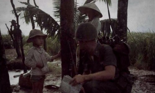Đại úy Donald T. Elledge, Cố vấn Hoa Kỳ của một tiểu đoàn bộ binh QLVNCH,trong chiến dịch hành quân tại Long An , dừng chân hỏi thăm một em bé Việt Nam.