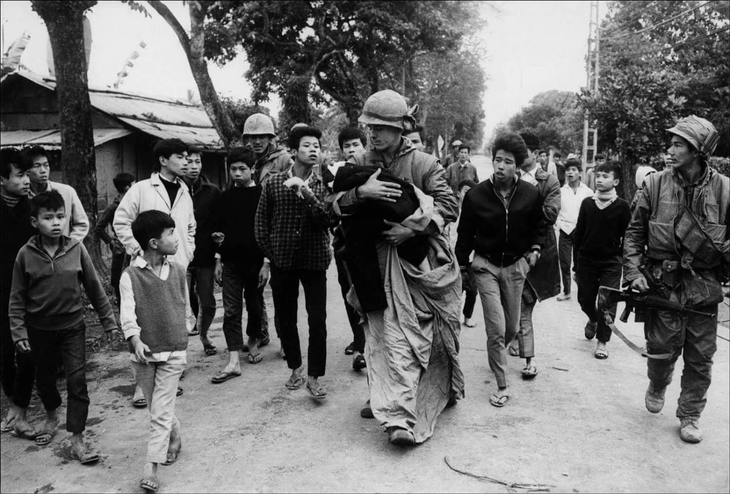 Một người lính Hoa Kỳ đang đưa 1 em bé người Việt ra khỏi khu vực giao tranh trong một trận đánh tại Huế...