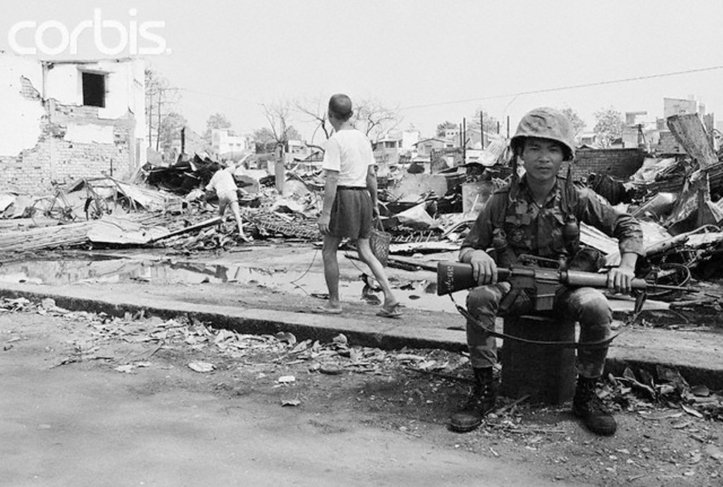 11.2.1968 - Trong tàn tích của Chợ Lớn. Sài Gòn: Một người lính Việt ngồi gần đống đổ nát của một số các tòa nhà bị phá hủy trong chiến đấu gần đây ở Chợ Lớn, khu phố Tàu của Saigon. Du kích csản biến khu vực này là một thành trì