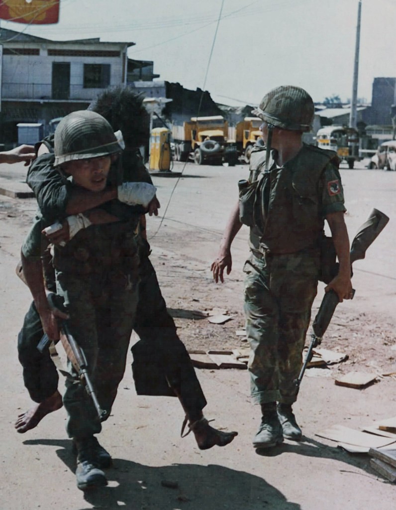 Saigon Tết Mậu Thân 1968 & An ARVN airborbe soldier carries a wounded captured NVA soldier piggyback to a shaded area for questioning and medical care.source: fold3.com