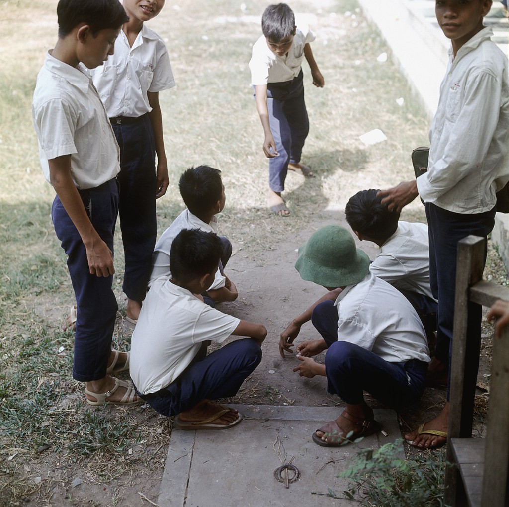 Schoolboys make a game where coins must be tossed, Vietnam, 1967.Học sinh chơi đánh đáo.