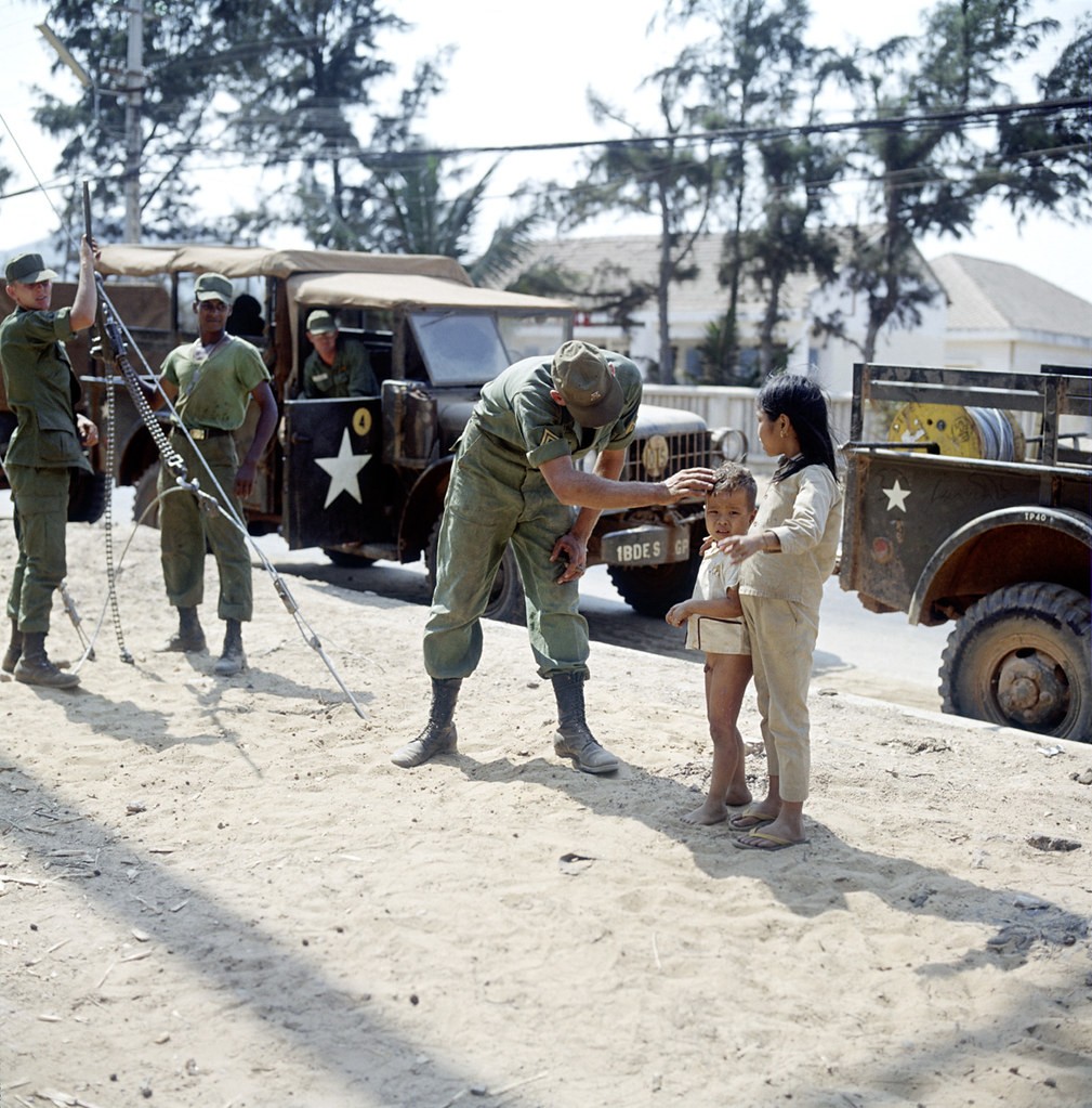 American soldiers and military vehicles and Vietnamese children, Vietnam, 1967. Đến gần lính Mỹ xin kẹo.