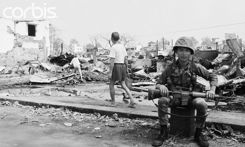11.2.1968 - Trong tàn tích của Chợ Lớn. Sài Gòn: Một người lính Việt ngồi gần đống đổ nát của một số các tòa nhà bị phá hủy trong chiến đấu gần đây ở Chợ Lớn, khu phố Tàu của Saigon. Du kích csản biến khu vực này là một thành trì