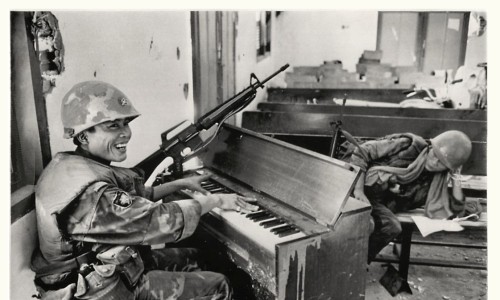 1968 - Vietnamese Marine plays shrapnel-marked pump organ amid ruins of Protestant church in Saigon
