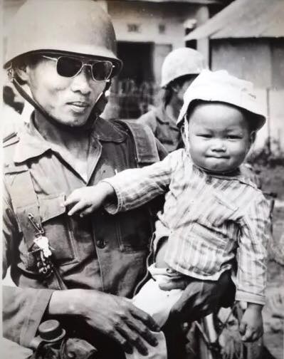 KonTum năm 1972.
Người lính chuẩn bị chiến đấu trong hệ thống phòng thủ KonTum đang ẵm con trên tay.
Gia đình anh và một số vợ con binh sĩ khác chấp nhận ở lại cùng chồng.