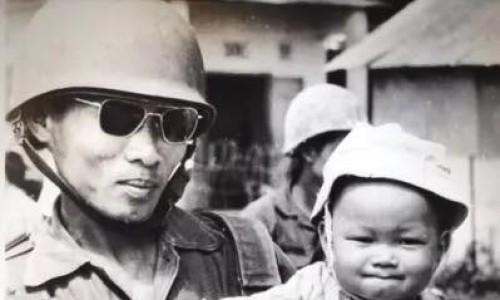KonTum năm 1972.
Người lính chuẩn bị chiến đấu trong hệ thống phòng thủ KonTum đang ẵm con trên tay.
Gia đình anh và một số vợ con binh sĩ khác chấp nhận ở lại cùng chồng.